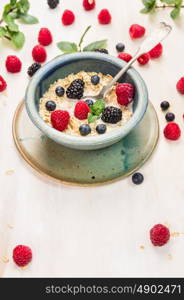 oat flakes with milk and berries in blue rustic bowl with spoon, breakfast background
