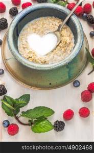 oat flakes with milk in a shape of heart on summer berries background