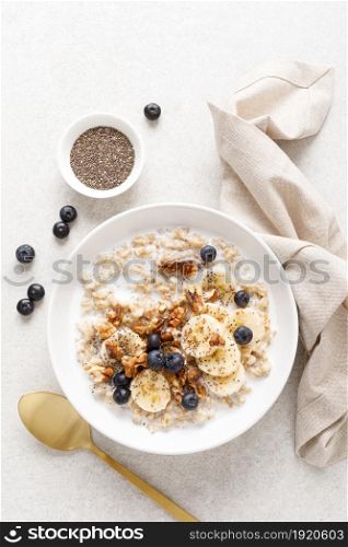 Oatmeal bowl. Oat porridge with banana, blueberry, walnut, chia seeds and almond milk for healthy breakfast or lunch. Healthy food, diet. Top view.