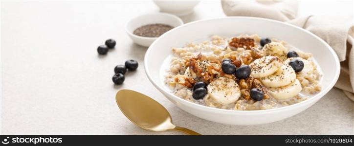 Oatmeal bowl. Oat porridge with banana, blueberry, walnut, chia seeds and almond milk for healthy breakfast or lunch. Healthy food, diet. Banner.