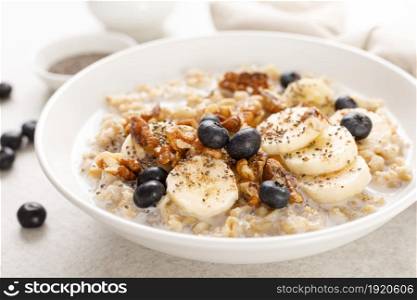 Oatmeal bowl. Oat porridge with banana, blueberry, walnut, chia seeds and almond milk for healthy breakfast or lunch. Healthy food, diet.