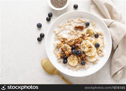 Oatmeal bowl. Oat porridge with banana, blueberry, walnut, chia seeds and almond milk for healthy breakfast or lunch. Healthy food, diet. Top view.
