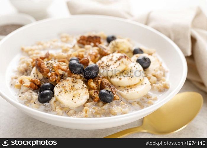 Oatmeal bowl. Oat porridge with banana, blueberry, walnut, chia seeds and almond milk for healthy breakfast or lunch. Healthy food, diet.