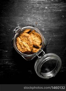 Oatmeal cookies in a jar. On a black wooden background.. Oatmeal cookies in a jar.