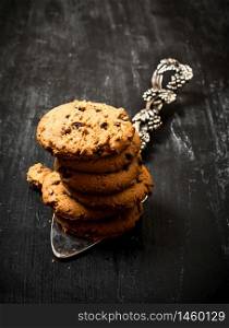 Oatmeal cookies on the blade. On a black wooden background.. Oatmeal cookies on the blade.