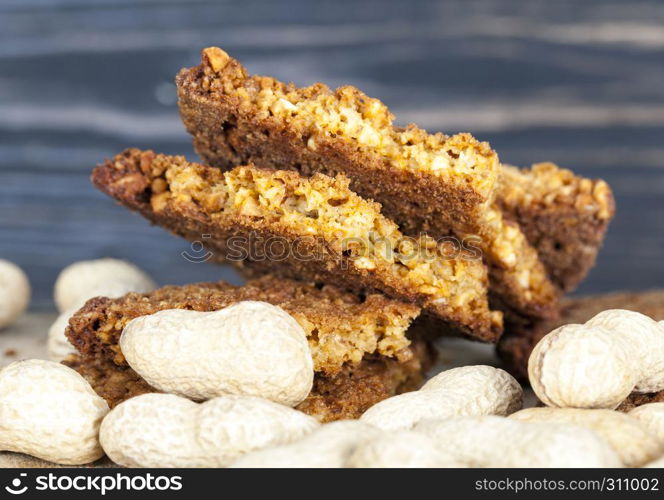 Oatmeal cookies with crushed peanuts lay with the body of the peanuts in the shell on the table. Oatmeal cookies with crushed peanuts