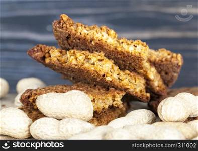 Oatmeal cookies with crushed peanuts lay with the body of the peanuts in the shell on the table. Oatmeal cookies with crushed peanuts