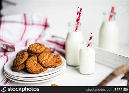 Oatmeal cookies with milk in jars on white wooden background