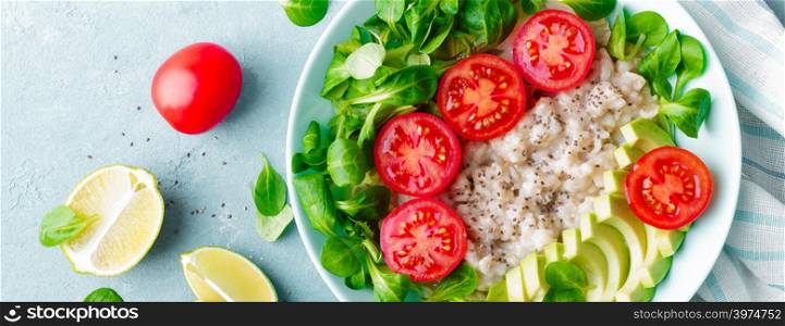 Oatmeal porridge with avocado and vegetable salad of fresh tomatoes and lettuce. Healthy dietary breakfast. Top view. Banner