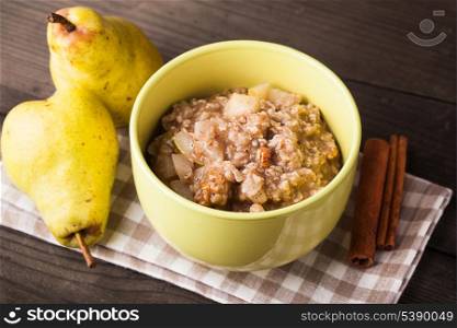 Oatmeal with pears and cinnamon and walnut on the wooden table