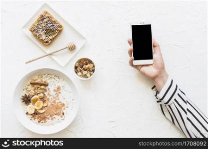 oatmeals dryfruits honeycomb table with cellphone hands