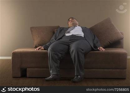 Obese businessman in formal clothes sleeping on sofa at home