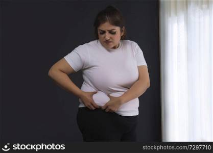 Obese Woman Holding His Belly Fat With Both Hands Giving An Expression Of Shock