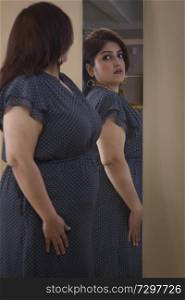Obese Woman trying dress in looking in mirror