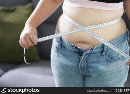Obese Woman with fat belly in dieting concept. Overweight woman touching his fat belly and want to lose weight. Fat woman her waist with a centimeter.Shape up healthy stomach muscle and diet lifestyle concept.
