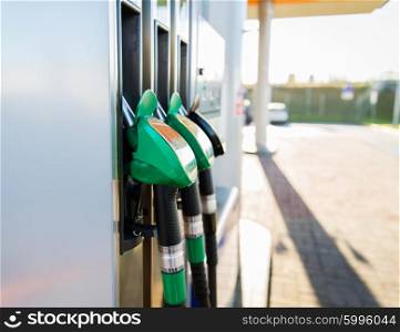 object, fuel, oil, tank and transport concept - close up of gasoline hose at gas station