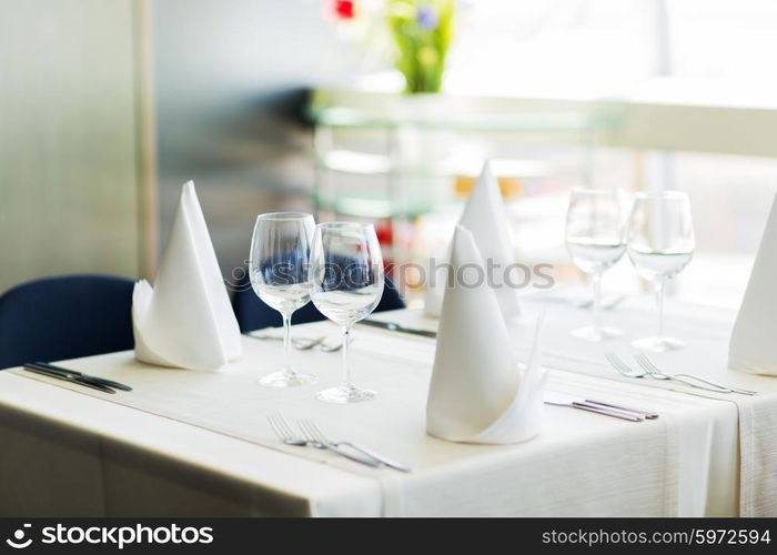 objects, dinnerware and holidays concept - close up of table setting with glasses, napkins and cutlery