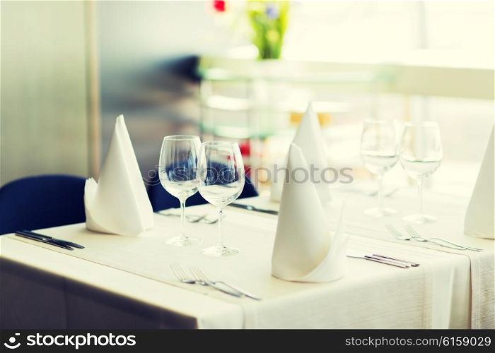 objects, dinnerware and holidays concept - close up of table setting with glasses, napkins and cutlery
