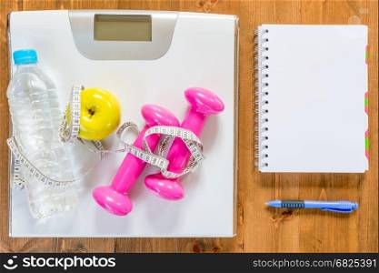 objects for weight loss and a notebook for recording the results of training on the wooden floor view from above