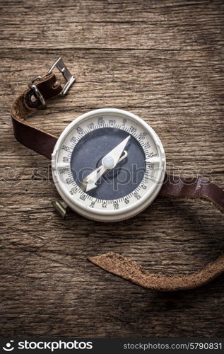 obsolete compass . obsolete compass with leather strap on wooden table top in retro style