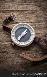obsolete compass . obsolete compass with leather strap on wooden table top in retro style