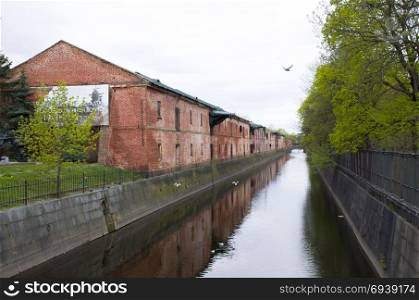Obvodny Canal protected old unplastered buildings from a red brick Admiralty warehouses in Kronddshtat Russia