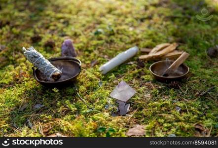 occult science and supernatural concept - close up of white sage in cup and stuff for magic ritual in forest. white sage in cup and magical stuff in forest