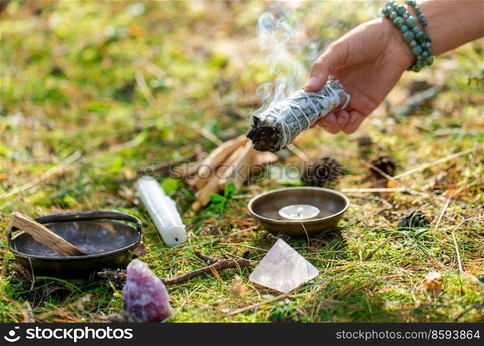 occult science and supernatural concept - close up of woman or witch with palo santo performing magic ritual in forest. woman or witch performing magic ritual in forest