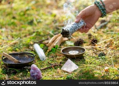 occult science and supernatural concept - close up of woman or witch with palo santo performing magic ritual in forest. woman or witch performing magic ritual in forest