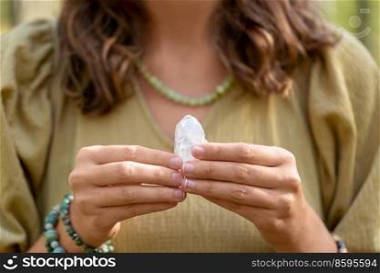 occult science and supernatural concept - close up of woman or witch with semiprecious crystal or gemstone performing magic ritual in forest. close up of woman holding magical crystal