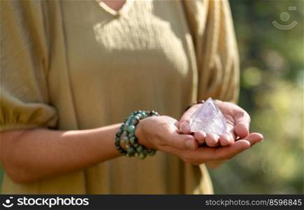 occult science and supernatural concept - close up of woman or witch with semiprecious crystal or gemstone pyramid performing magic ritual in forest. close up of woman holding crystal pyramid
