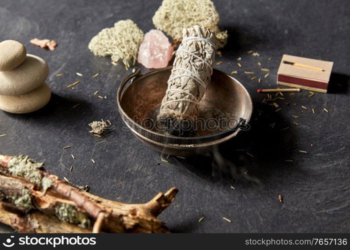 occult science and supernatural concept - smoking white sage in cup and staff for magic ritual. smoking white sage in cup and other magic staff