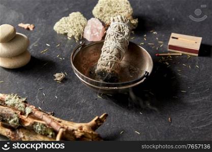 occult science and supernatural concept - smoking white sage in cup and staff for magic ritual. smoking white sage in cup and other magic staff