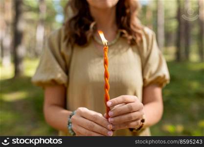 occult science and supernatural concept - woman or witch with candle performing magic ritual in forest. woman with candle performing magic ritual
