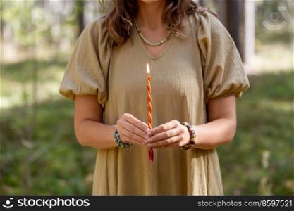 occult science and supernatural concept - woman or witch with candle performing magic ritual in forest. woman with candle performing magic ritual