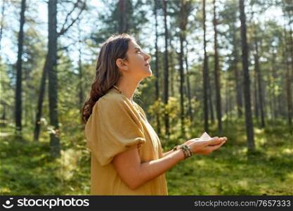 occult science and supernatural concept - young woman or witch with pyramid performing magic ritual in forest. young woman or witch holding pyramid in forest