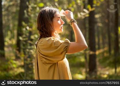 occult science and supernatural concept - young woman or witch with semiprecious crystal or gemstone performing magic ritual in forest. woman or witch performing magic ritual in forest