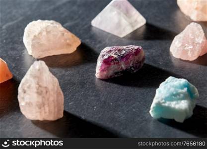 occult science, minerals and geology concept - quartz crystals and gem stones on slate background. quartz crystals and gem stones on slate background