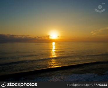 Ocean sunset. Sun over horizon reflecting on water surface.