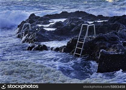 Ocean waves and stairs in public pool of Termas da Ferraria, Sao Miguel island, Azores&#xA;