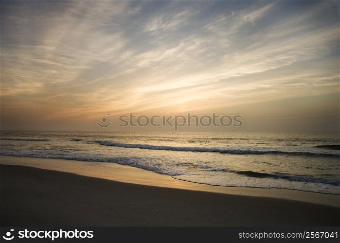 Ocean waves lapping on the shore at sunset.
