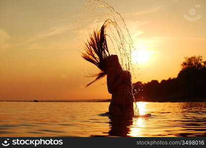 ocean woman in sunrise light splashing hair