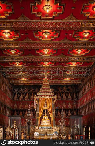 OCT 24, 2019 Bangkok, Thailand - Bangkok National Museum Thai antique Siamese Phra Phuttha Sihing royal Buddha sculpture under red gold pavillion with golden mural painting and ceiling