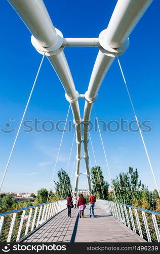 OCT 26, 2012 Valencia, Spain - White suspension bridge in Valencia Bioparc with tourists walking under blue sky in autumn