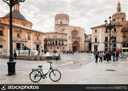 Oct 30, 2012 Valencia, Spain - Fuente del Turia fountain, bicycle and tourists at Valencia Cathedral square with church and bell tower in background. Most famous attraction in old town area