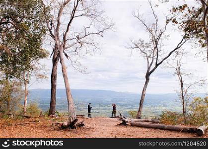 OCT 30, 2019 Loei - Thailand - Leafless tree and mountain view with tourists at Sam Haek nature trail rest point at Phu Kradueng National park.