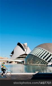 OCT 31, 2012 Valencia, Spain - People riding bicycle at City of Arts and Sciences and blue pool under blue sky. Architecture designed by Santiago Calatrava and Felix Candela