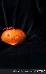 October 31, Halloween - Old Jack-o-Lantern on a black background. The spider sits on a pumpkin. Place for an inscription. October 31, Halloween - Old Jack-o-Lantern on a black background. The spider sits on a pumpkin. Place for an inscription.