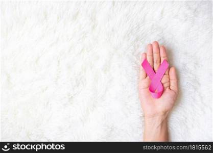October Breast Cancer Awareness month, adult Woman hand holding Pink Ribbon on pink background for supporting people living and illness. International Women, Mother and World cancer day concept