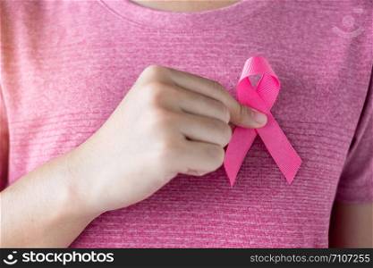 October Breast Cancer Awareness month, Woman in pink T- shirt with hand holding Pink Ribbon for supporting people living and illness. Healthcare, International Women day and World cancer day concept